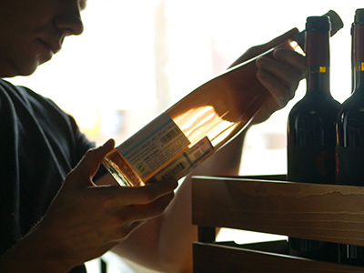 A person looking closely at labels on a wine bottle